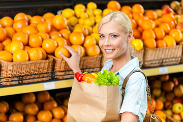 Obraz premium Choosing oranges girl hands bag with fresh vegetables 