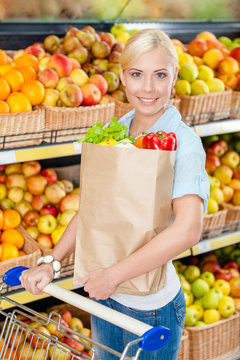 Girl with cart hands bag with fresh vegetables