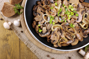Delicious fried mushrooms in pan on table close-up