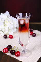 Glass of cocktail on table on dark red background