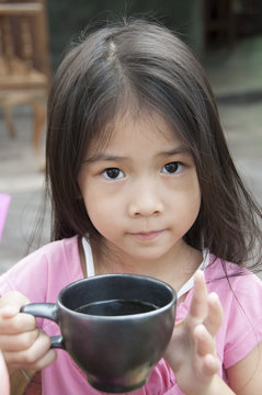 Little Asian girl with a cup of cocoa.