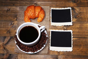 Coffee cup, bun and old blank photos, on wooden background