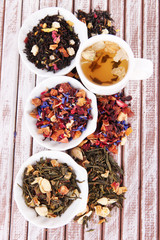 Cup of tea with aromatic dry tea in bowls on wooden background