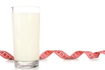 Glass of milk with measuring tape isolated on white
