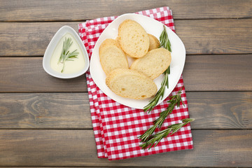 Fresh bread with olive oil and rosemary on wooden table