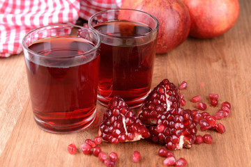 Ripe pomegranates with juice on table close-up