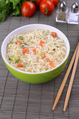 Tasty instant noodles with vegetables in bowl on table close-up