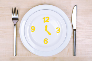Plate with clock on wooden table close-up