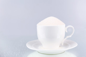 Sugar in cup on grey background