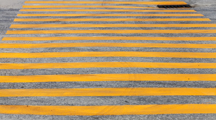 Pedestrian crossing road marking with yellow stripes on asphalt