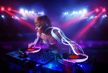 Obraz na płótnie Canvas Disc jockey girl playing music with light beam effects on stage