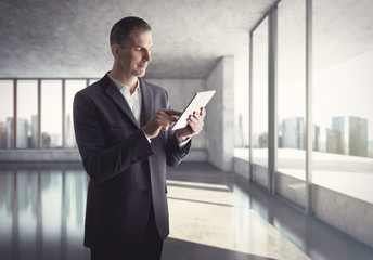 Businessman with tablet computer standing in bright office