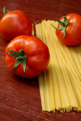 tomatoes and raw pasta on wooden table
