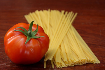 tomato and raw pasta on wooden background
