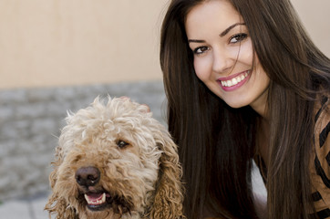 Portrait of a beautiful young woman smiling playing with a dog.