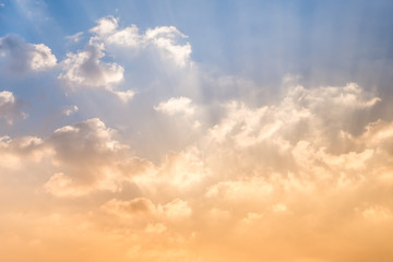 Golden rays shine clouds under blue sky