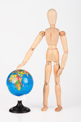 Brown wood mannequin standing concerned next to globe