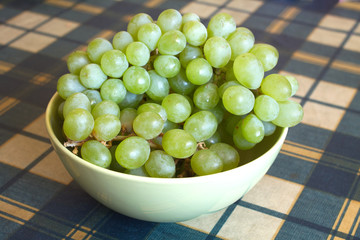 Grape оn branch in green bowl on checkered tablecloth