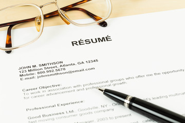 Resume with pen and glasses on table closeup