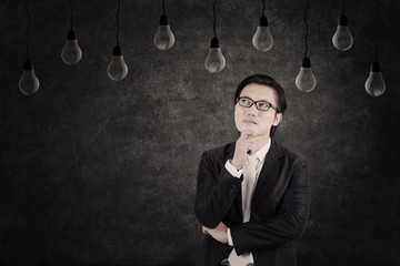 Businessman looking at unlit lightbulb