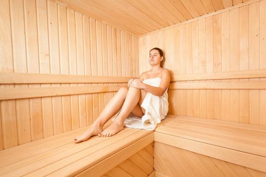 Beautiful slim woman sitting in wooden steam bath