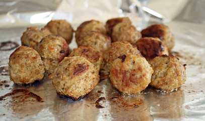 Sizzling hot meatballs cooking on foil in the oven
