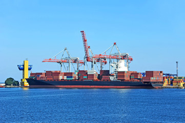 Fototapeta premium Container stack and ship under crane bridge