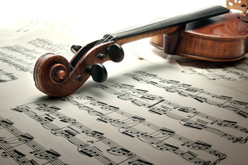 Detail of old scratched violin with sheet music. Vintage style.