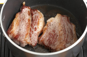 cooking beef in black pan in kitchen