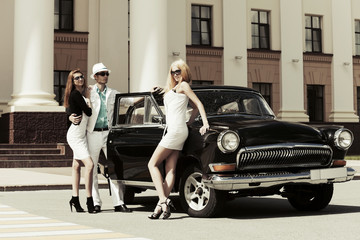 Young fashionable people at the retro car