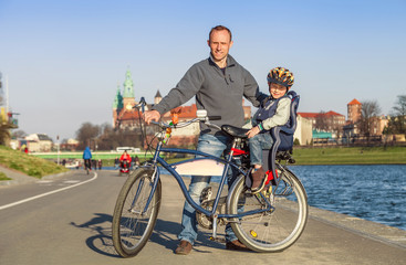 Obraz premium Father with little son walk togeter on bike in city