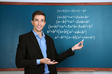Teacher explaining formulas written on blackboard to  pupils