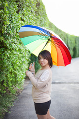 Asian woman holding an umbrella on the sidewalk.