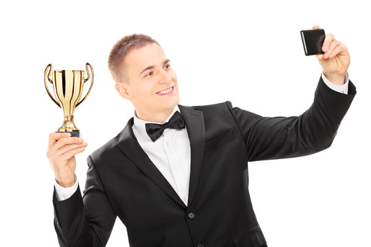 Elegant male holding trophy and taking a selfie