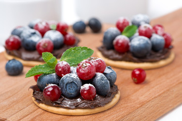 cake with chocolate cream and berries on wooden board