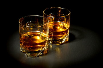 Two glasses of whiskey on black table