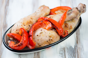 Baked chicken legs with grilled bell pepper slices, studio shot