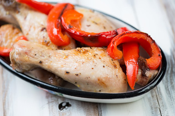 Close-up of baked chicken legs with slices of grilled pepper