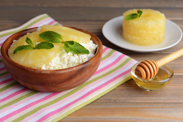Bowl of tasty cottage cheese with pineapple on wooden table