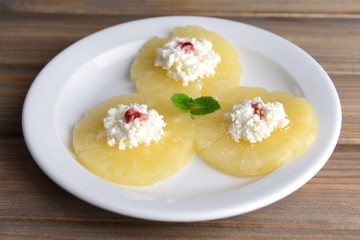 Tasty pineapple with cottage cheese on  wooden table