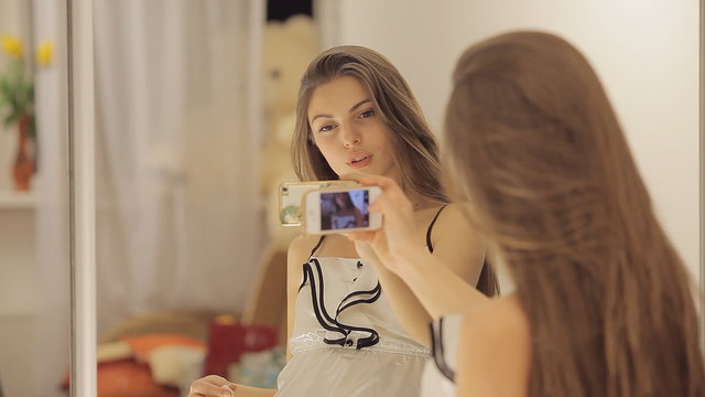 Young girl dances and takes a photo of herself before the mirror