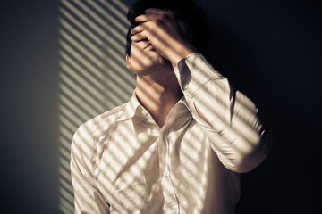 Man by window with shadows from blinds