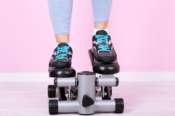 Woman doing exercise on stepper. Close-up on legs.