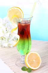 Glass of cocktail on table on light blue background