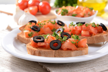 Delicious bruschetta with tomatoes on plate on table close-up