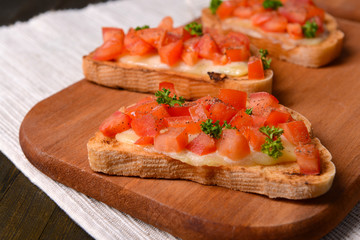 Delicious bruschetta with tomatoes on cutting board close-up