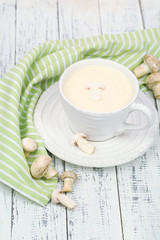 Delicate mushroom sauce in cup on wooden table close-up