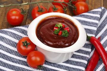Tomato sauce in bowl on wooden table close-up