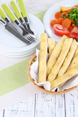 Bread sticks  in wicker basket on wooden background
