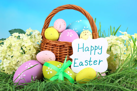 Easter composition with eggs on green grass, on blue background